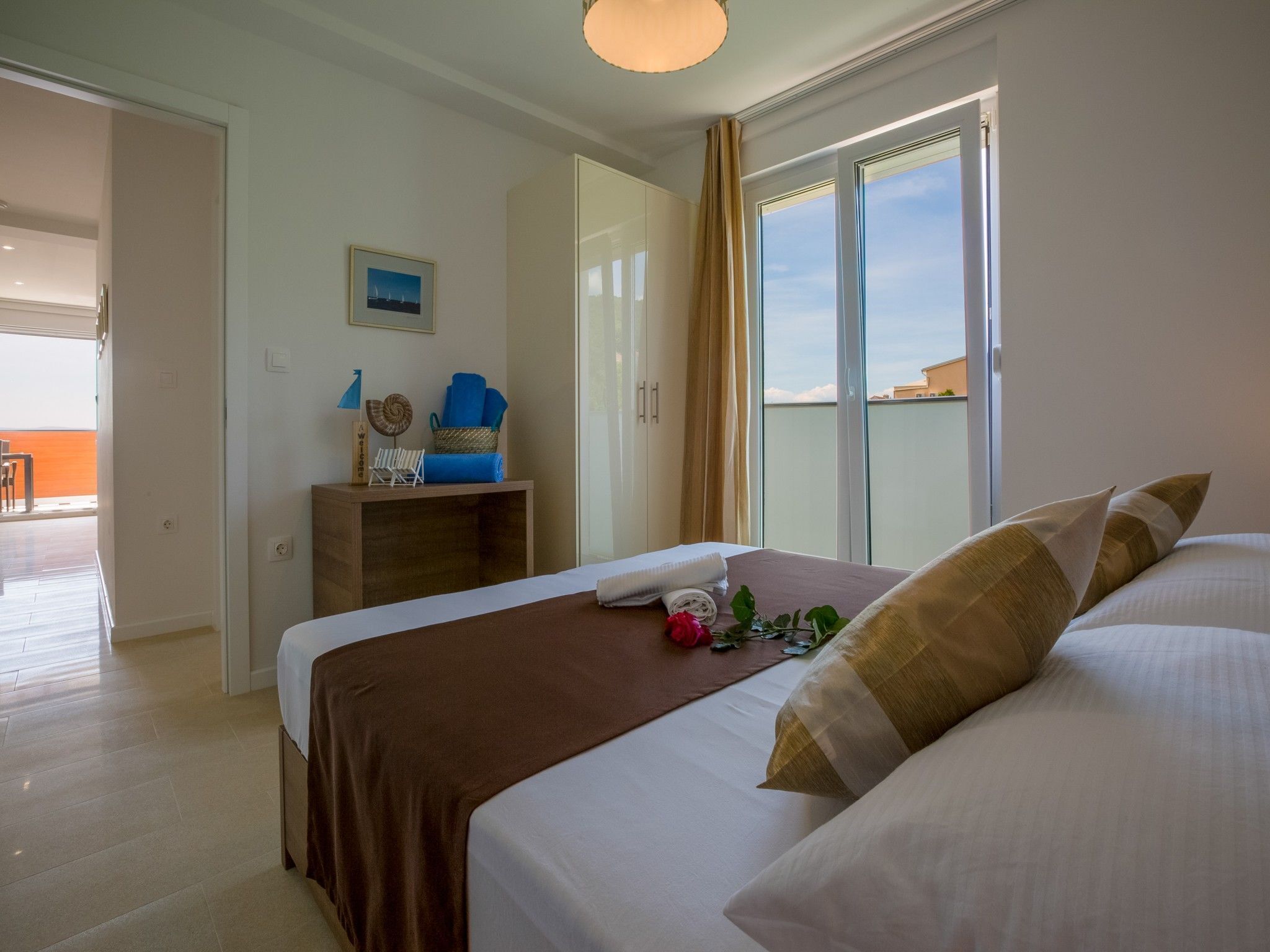 A hotel room with a large bed, a desk with a chair, a window with curtains, and a view of the outside.