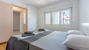 Un dormitorio con cama, almohadas, una manta y ventana.