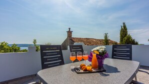 Una mesa con bandeja para bebidas, vasos y un arreglo floral en una terraza con vistas panorámicas.