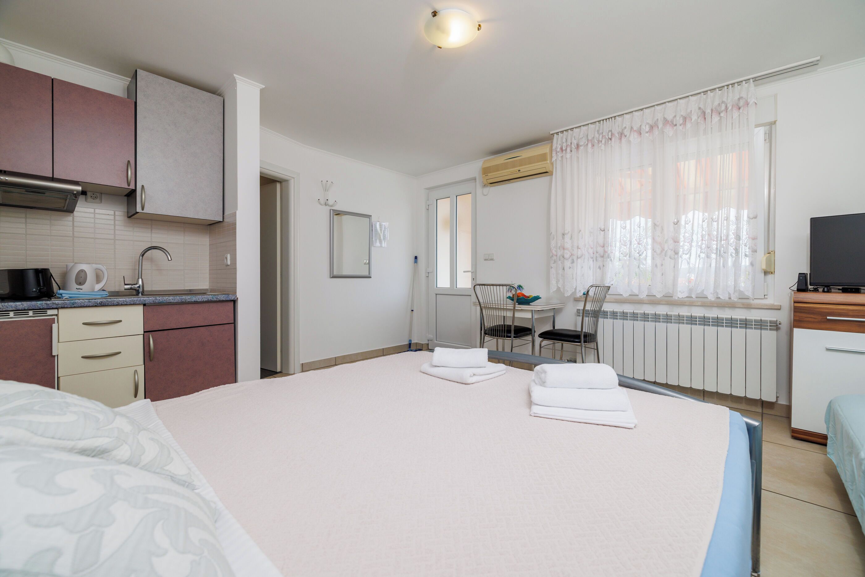 Een hotelkamer met een bed, een klein kitchenette, een eethoek en een televisie.