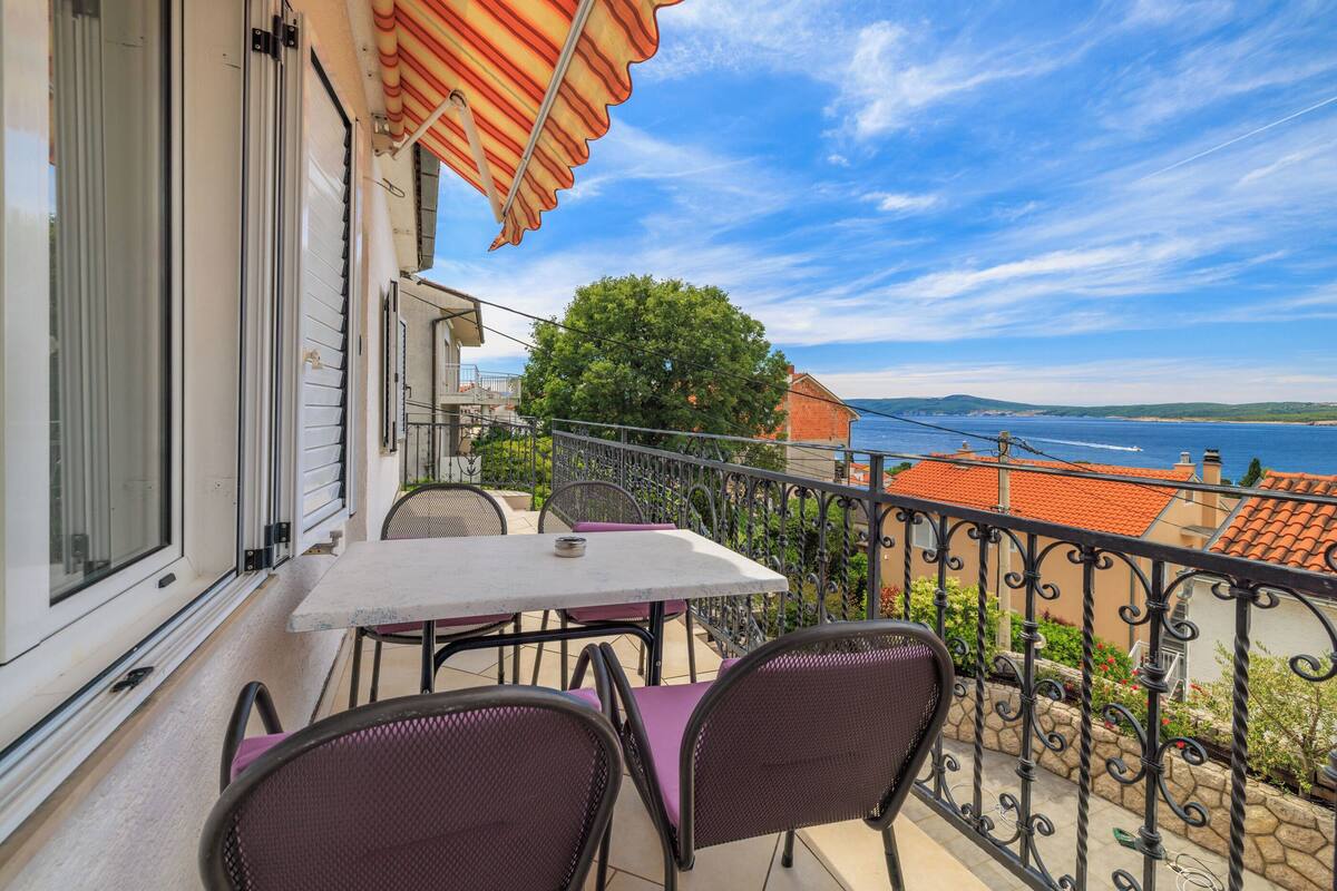 Un balcon avec une table et des chaises, offrant une vue sur la côte.