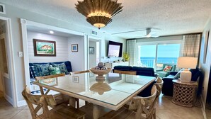 A dining area with a glass-top table, wooden chairs, and a decorative bowl centerpiece. - 11th floor paradise! (Panama City Beach)