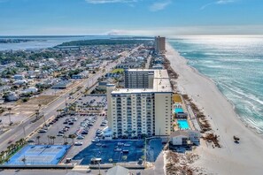 A coastal hotel with a large parking lot, a swimming pool, and a beachside location.