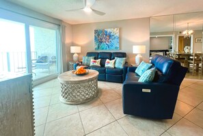 Relax in this stylish living room with a sofa, coffee table, and abstract art, complemented by a dining area and comfortable seating options.