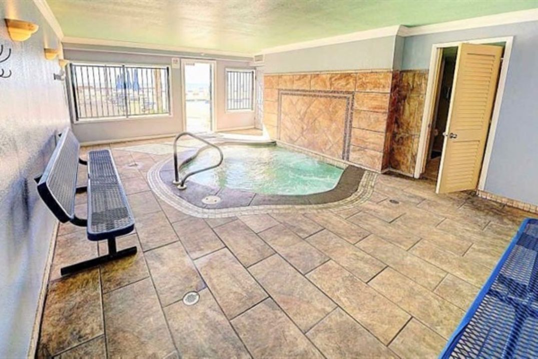 Un área de spa con una bañera de hidromasaje, un banco y una puerta.