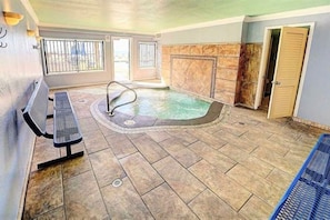 Un espace bien-être comprenant un jacuzzi, un banc et une porte.