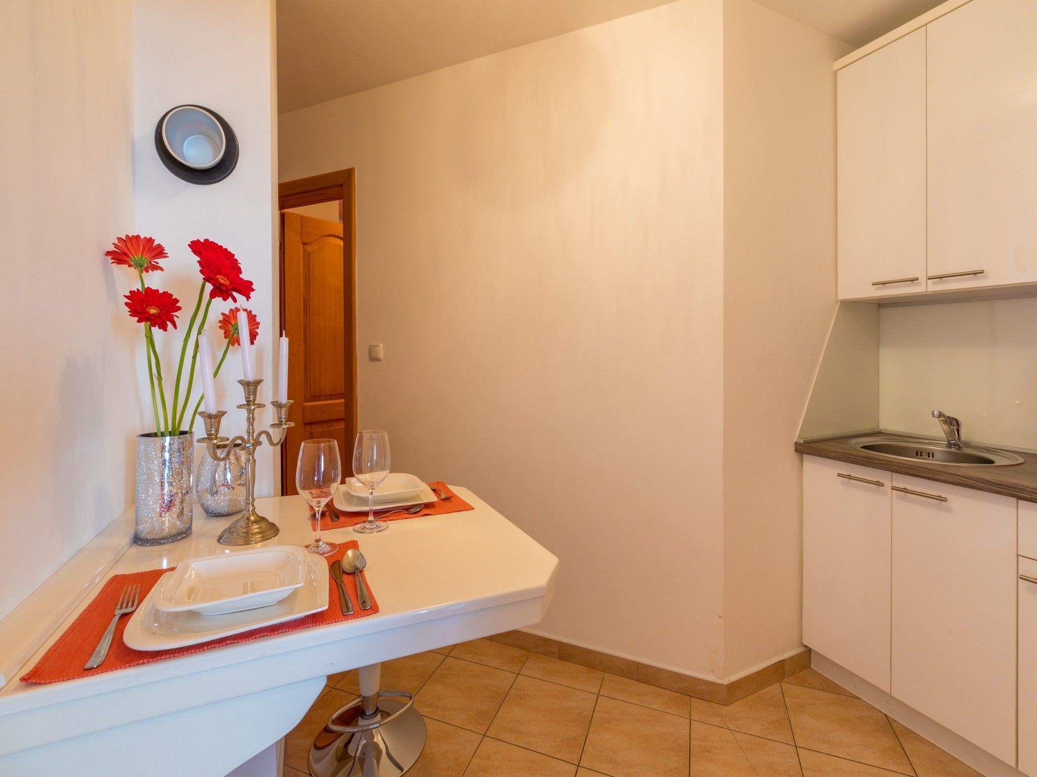 A kitchen with a dining area, including a table set with plates, glasses, and cutlery.
