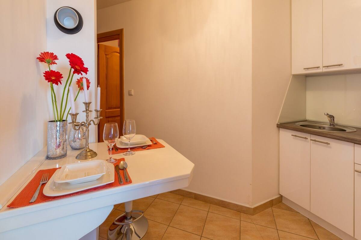 A kitchen with a dining area, including a table set with plates, glasses, and cutlery.
