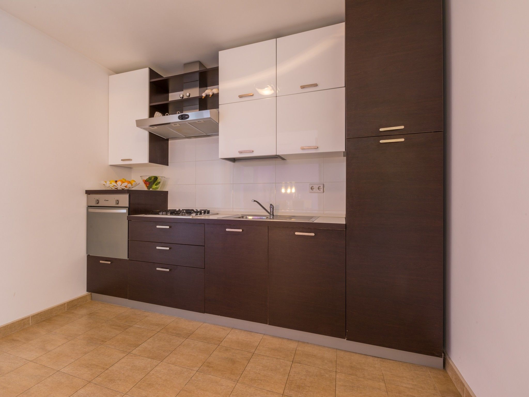 A modern kitchen with dark cabinetry, a gas stove, a built-in oven, and a stainless steel sink.