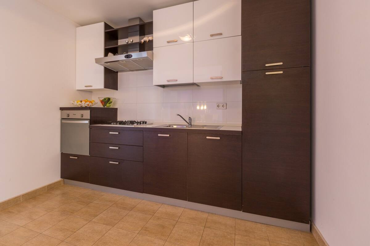 A modern kitchen with dark cabinetry, a gas stove, a built-in oven, and a stainless steel sink.