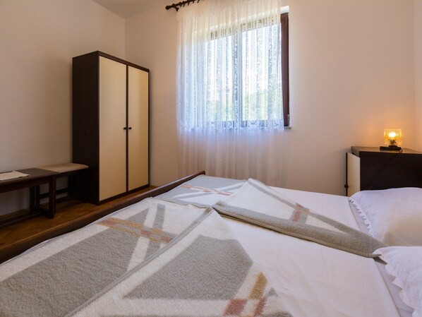 A bedroom with a bed, a wardrobe, a desk, and a window with curtains. - Apartments Ankica (Crikvenica)