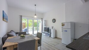 A modern kitchen with a dining area, a built-in TV, and a refrigerator. - Apartments Ankica (Crikvenica)