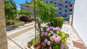 A residential street with a row of potted plants and a car parked on the sidewalk. - Apartments Ankica (Crikvenica)