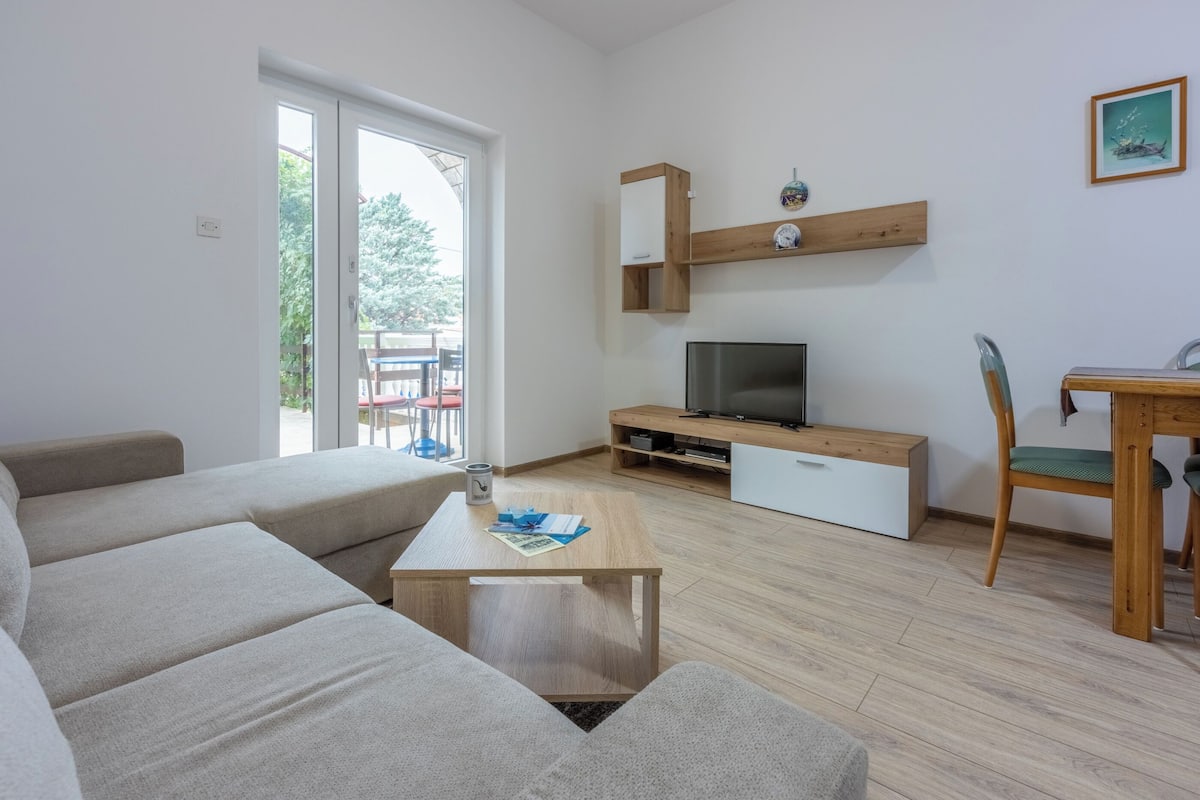 Una sala moderna con sofá, mesa de centro, mueble para TV y mesa de comedor de madera.