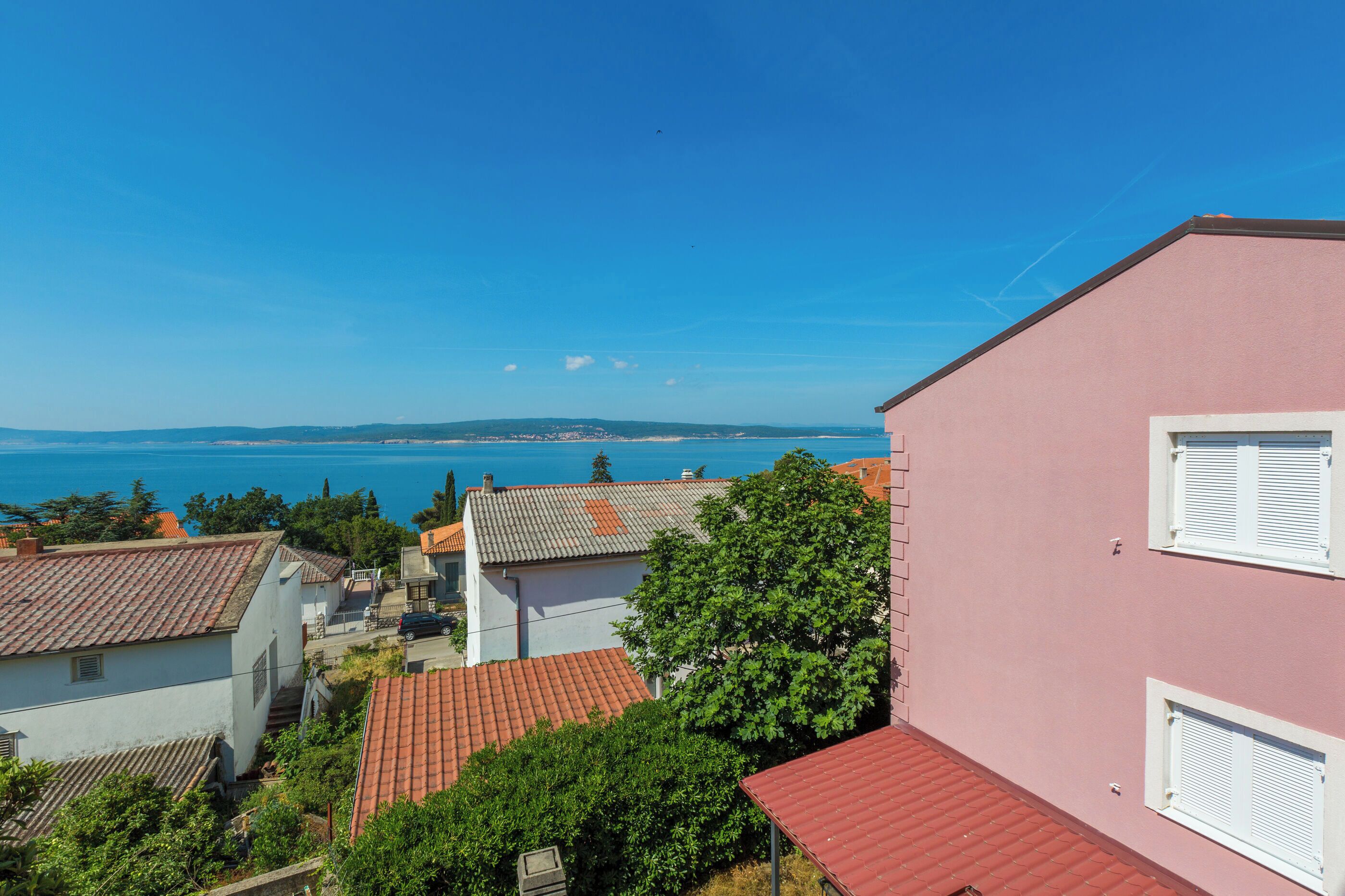 A coastal residential area with houses, a pink building, and a view of the sea.