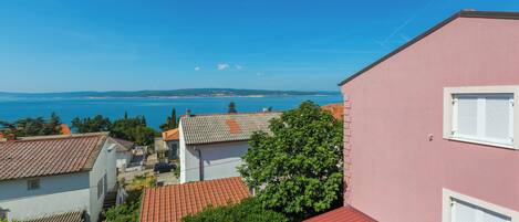 A coastal residential area with houses, a pink building, and a view of the sea.