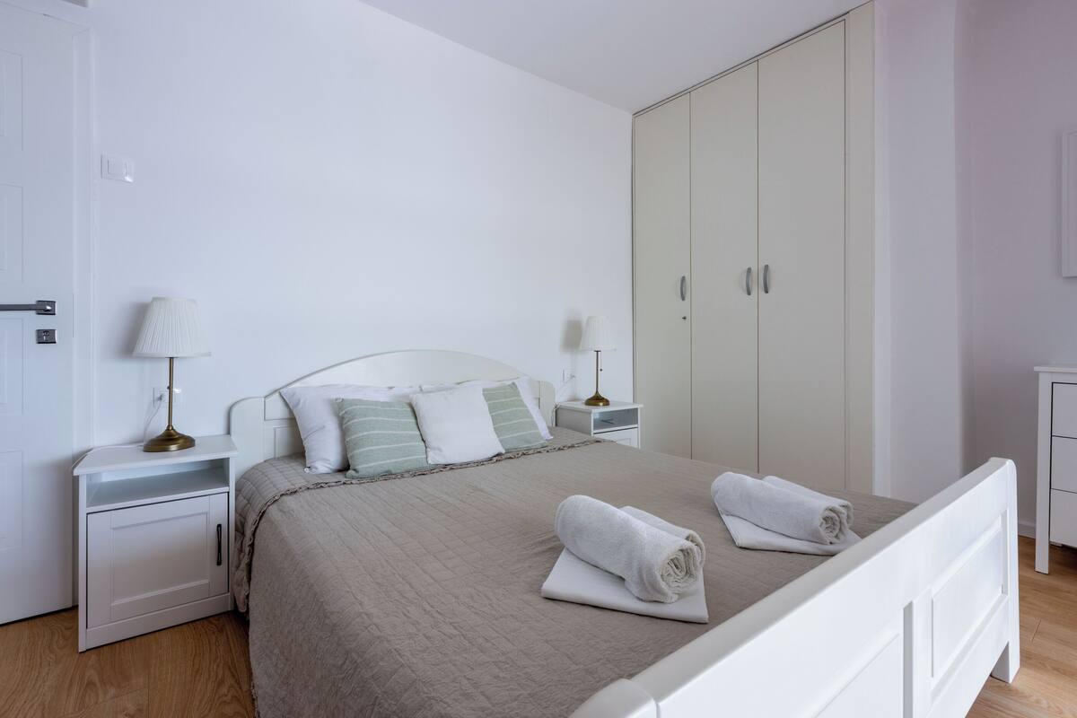 A neatly arranged bedroom with a bed, nightstands, a wardrobe, and a lamp.