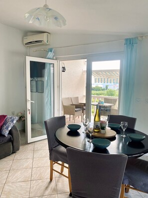 A dining area with a round table, chairs, and a view through a glass door to an outdoor patio.