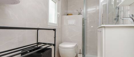 Une salle de bain moderne équipée de toilettes, d’une douche et d’un lavabo.