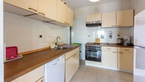 A kitchen with wooden cabinets, a dishwasher, an oven, and a coffee maker.