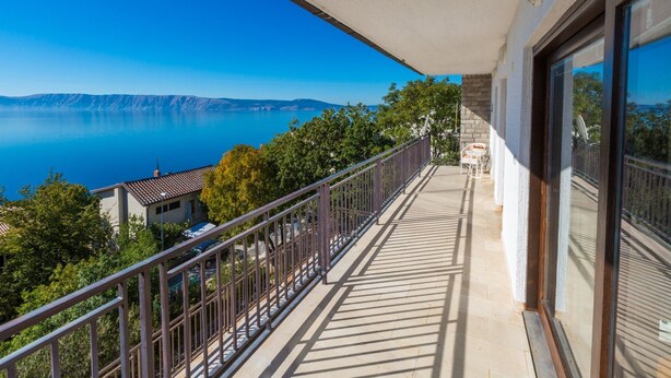 A balcony with a clear view of a lake and distant mountains.