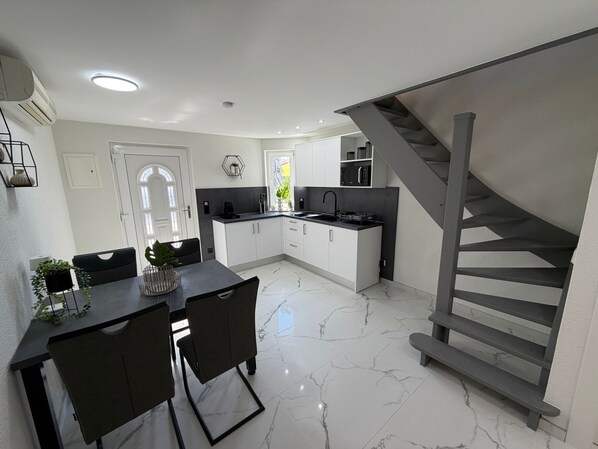 A modern kitchen with white cabinets, a black countertop, and a stainless steel sink.