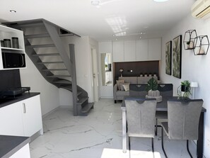 A modern kitchen with a built-in microwave, a dining area with a table and chairs, and a staircase leading to an upper level. - Apartments Fijala (Crikvenica)