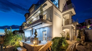 A modern two-story villa with a balcony, stone steps, and potted plants. - Apartments Fijala (Crikvenica)