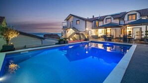 A large swimming pool with a two-story house in the background. - Apartments Fijala (Crikvenica)