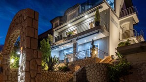 A multi-story building with a stone facade, balconies, and outdoor lighting. - Apartments Fijala (Crikvenica)