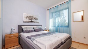 Ein Schlafzimmer mit Bett, Nachttisch, Lampe und einem Bild an der Wand.