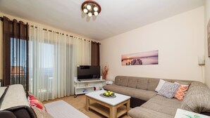 Ein Wohnzimmer mit einer Couch, einem Couchtisch, einem Fernseher und einem Bild an der Wand.