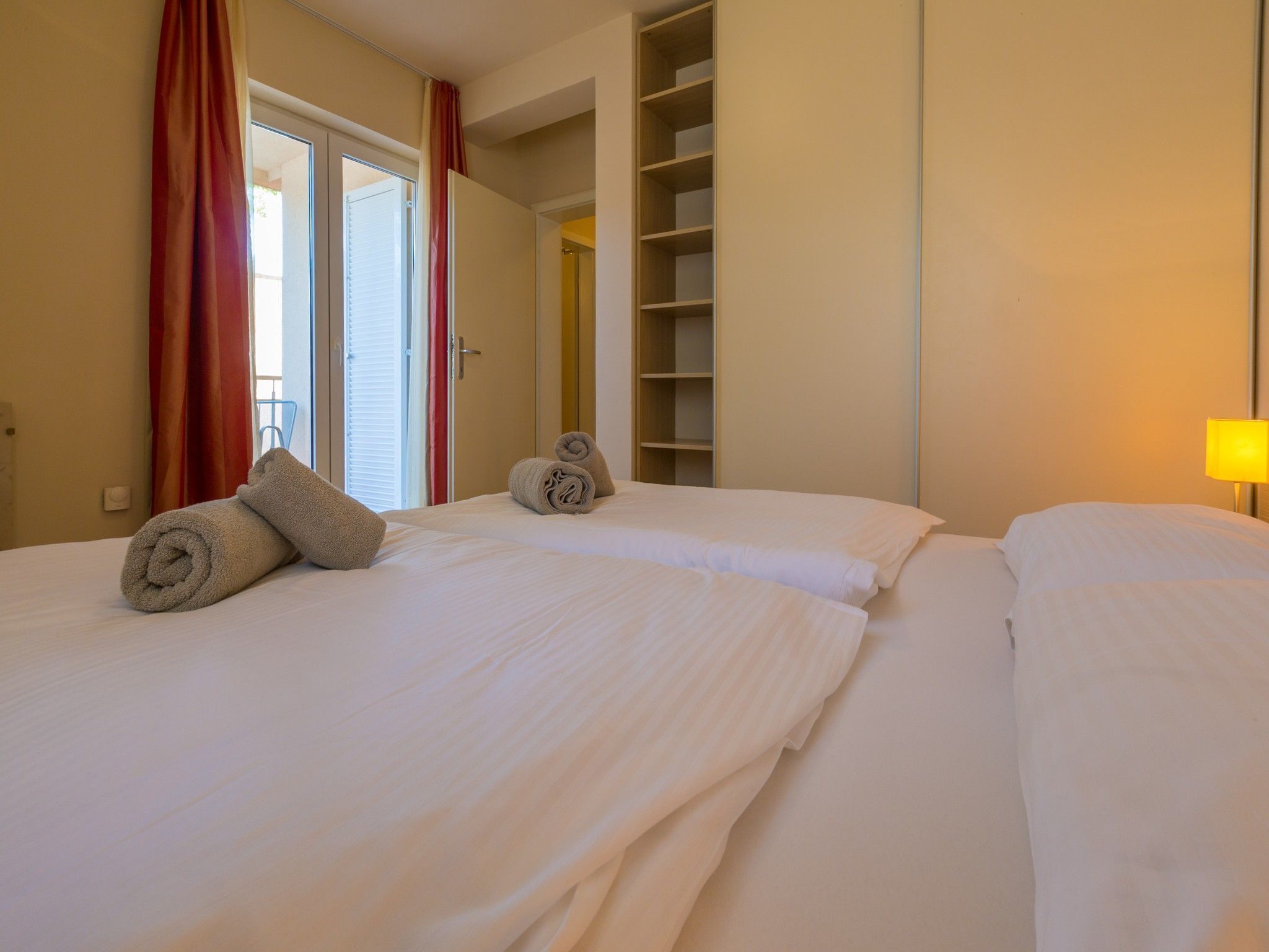 Ein Hotelzimmer mit zwei Betten, einem Kleiderschrank und einem Fenster mit Vorhängen.