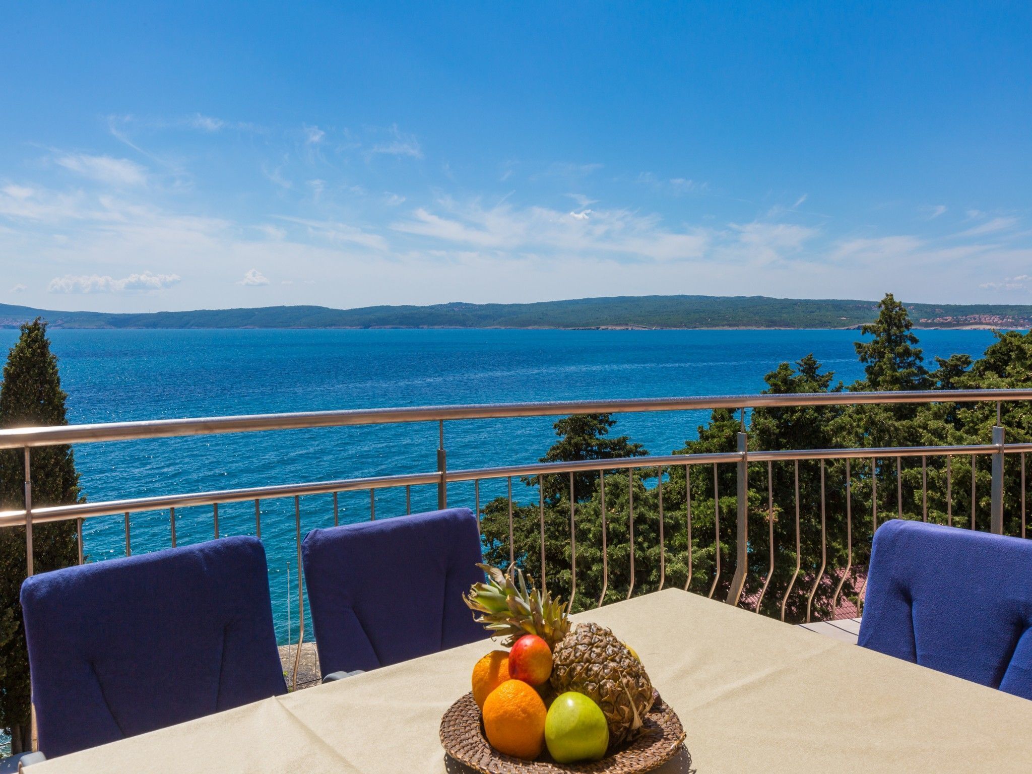Ein Tisch mit Obstkorb auf einem Balkon mit Blick auf das Meer.