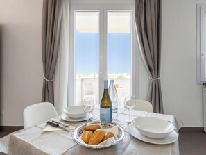 Un tavolo da pranzo con una bottiglia di vino, bicchieri, piatti e un cesto di pane.