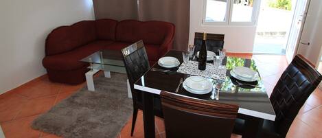 Un coin repas avec une table en verre, des chaises noires et un canapé rouge.
