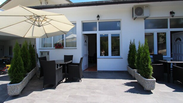 Eine Terrasse mit Sitzgelegenheiten im Freien, einem großen Sonnenschirm und Blumentöpfen.