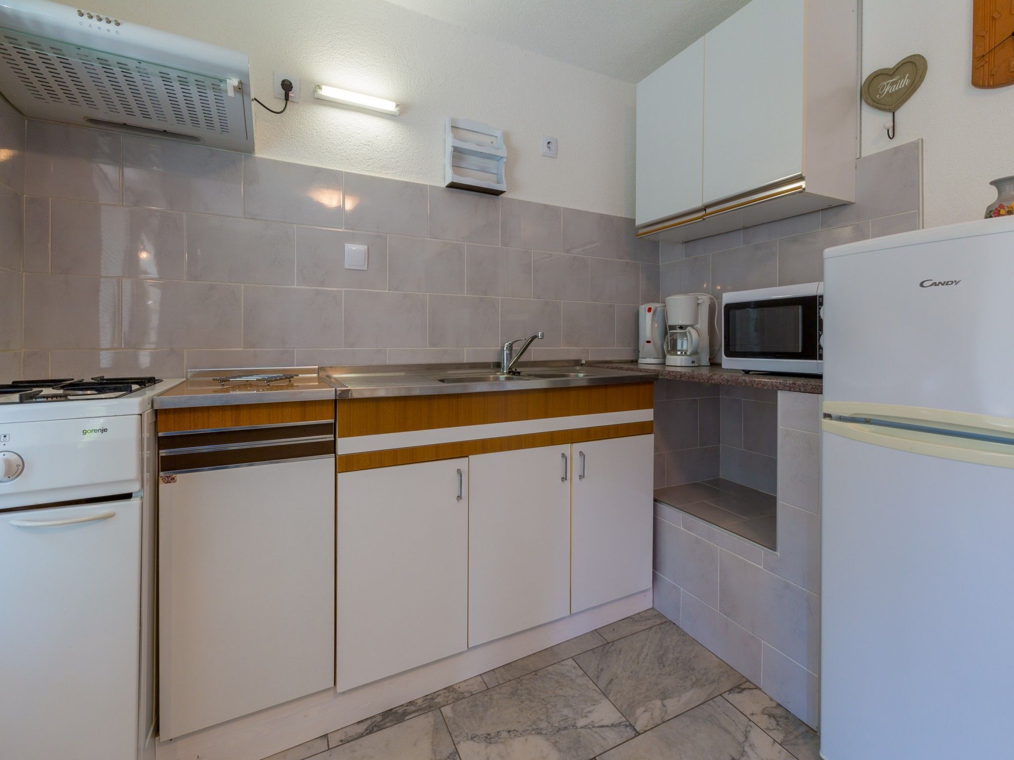 A kitchen with white cabinets, a stove, a microwave, and a coffee maker.