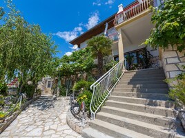 A stone-paved pathway leading to a building with a metal staircase and a balcony.