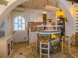 A kitchen with a stone island, white cabinets, and a window.