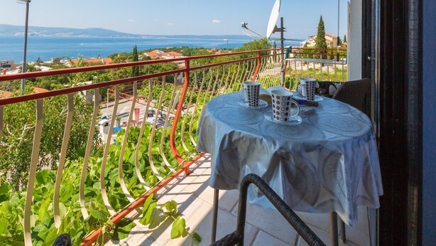 Ένα μπαλκόνι με ένα τραπέζι στρωμένο για δύο άτομα, με θέα στην ακτογραμμή.