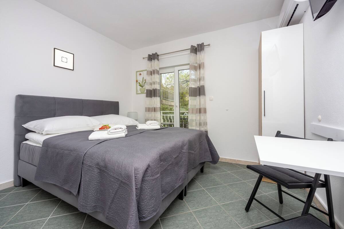 A bedroom with a bed, a desk, and a chair.