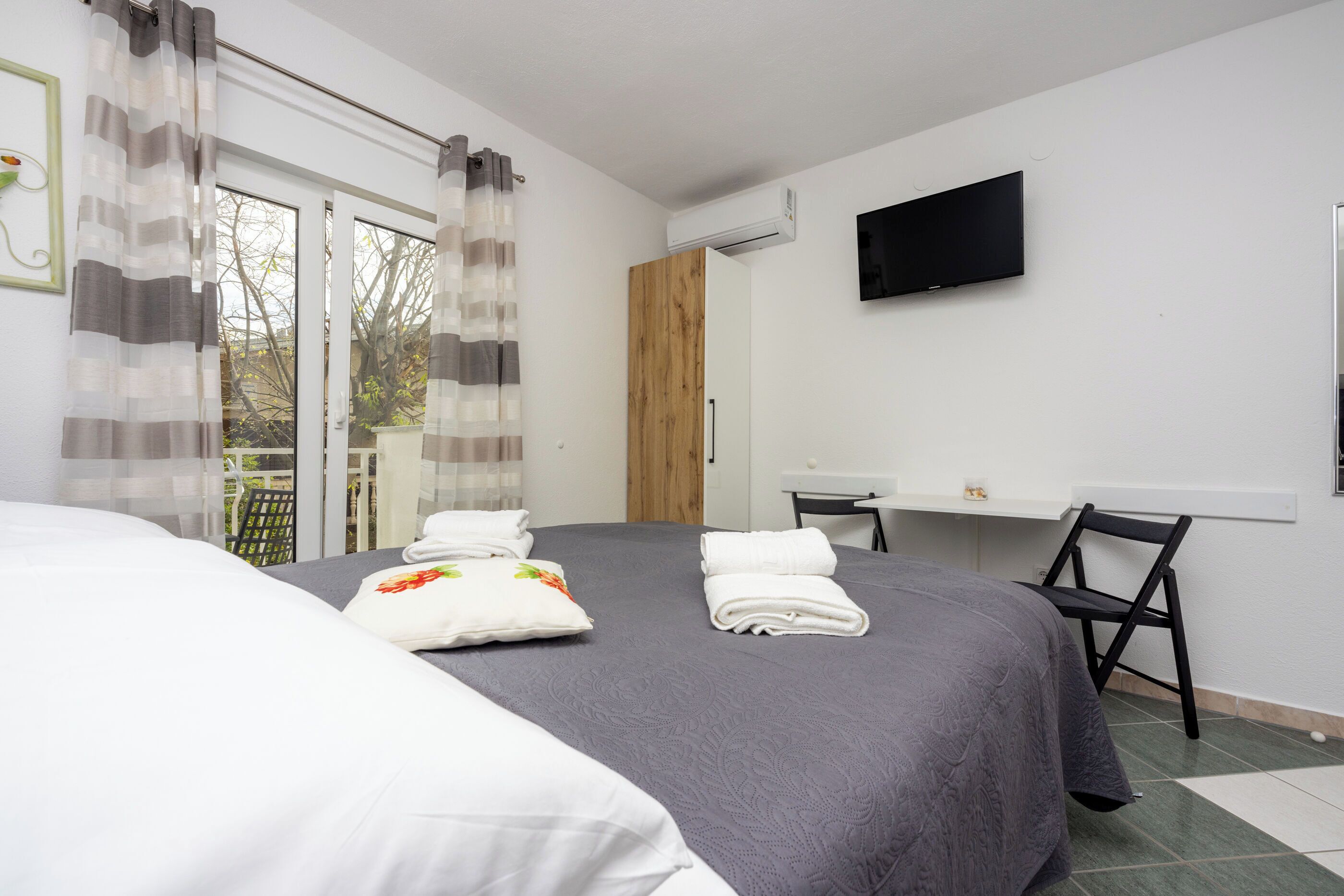 Una camera d'albergo con un letto grande, una scrivania, una sedia e una TV appesa al muro.