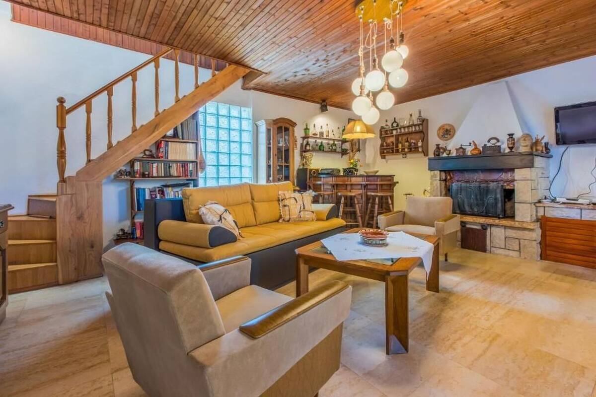 A cozy living room with a wooden staircase, a sofa, a coffee table, and a fireplace.