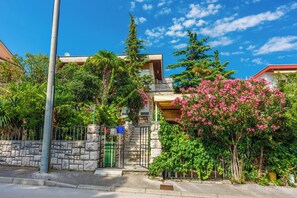 A residential building with a stone wall, a metal gate, and a balcony.