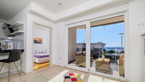 A modern living room with a sofa, a coffee table, and a view of the outside balcony. - Apartment Jana (Crikvenica)