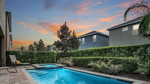 A rectangular swimming pool with a brick border, surrounded by a hedge and a building. - 8BR Superb Villa, Pool, Spa • Near Disney (Kissimmee)