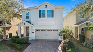 A two-story house with a garage, a front porch, and a brick driveway. - 8BR Superb Villa, Pool, Spa • Near Disney (Kissimmee)