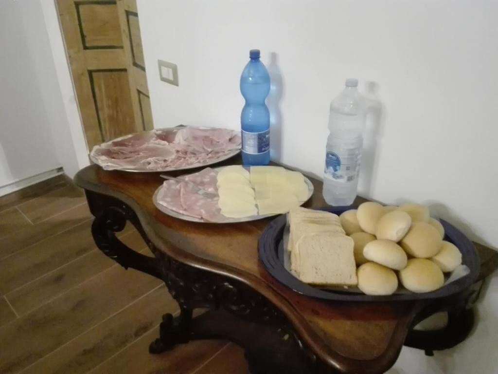 Una mesa de comedor con platos de comida, una botella de agua y un bol de panecillos.