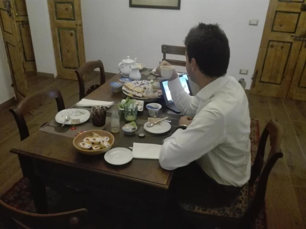 A dining table with plates, a laptop, and a teapot.